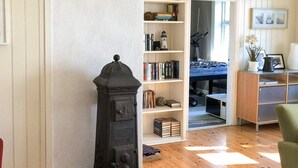 A room with a vintage stove, wooden shelves with books, a desk with a lamp, and a chair. - 7 Person Holiday Home in Fiska (Vanylven)