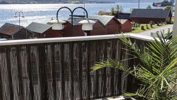 A coastal view with a wooden fence, lamp posts, and a ship docked in the background. - 7 Person Holiday Home in Fiska (Vanylven)