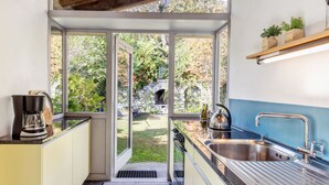 Une cuisine moderne dotée d’une grande fenêtre, d’une machine à café, d’une bouilloire et d’un évier.