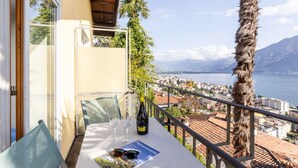 Un balcon avec une table dressée pour deux personnes, une bouteille de vin et une paire de lunettes de soleil.