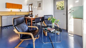 Une cuisine moderne avec un coin repas, dotée d’un plafond en bois, d’un canapé en cuir noir, d’une table basse en verre et d’un vase rempli de fleurs.