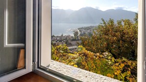 Une vue depuis une fenêtre donnant sur une ville, avec des montagnes en arrière-plan.