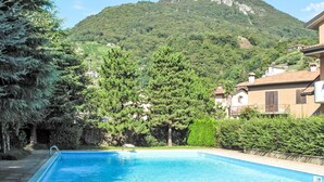 A swimming pool with a mountain backdrop, surrounded by trees and residential buildings.