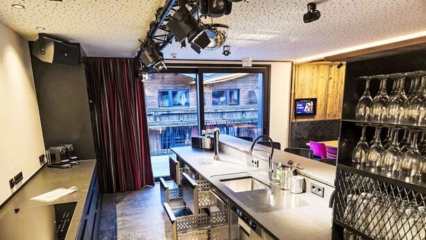 A modern kitchen with stainless steel appliances, a large window, and a wine rack.
