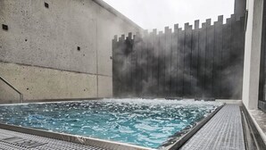 A hot tub with a concrete wall and a wooden fence in the background.