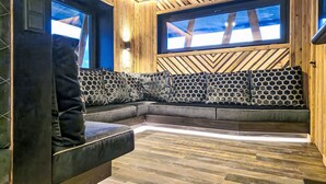 A modern interior with a wooden ceiling, a large window, and a sectional sofa with patterned cushions.