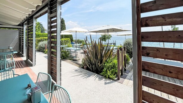 Un espace extérieur aménagé en terrasse, avec des tables et des chaises, une piscine et une vue sur la mer.