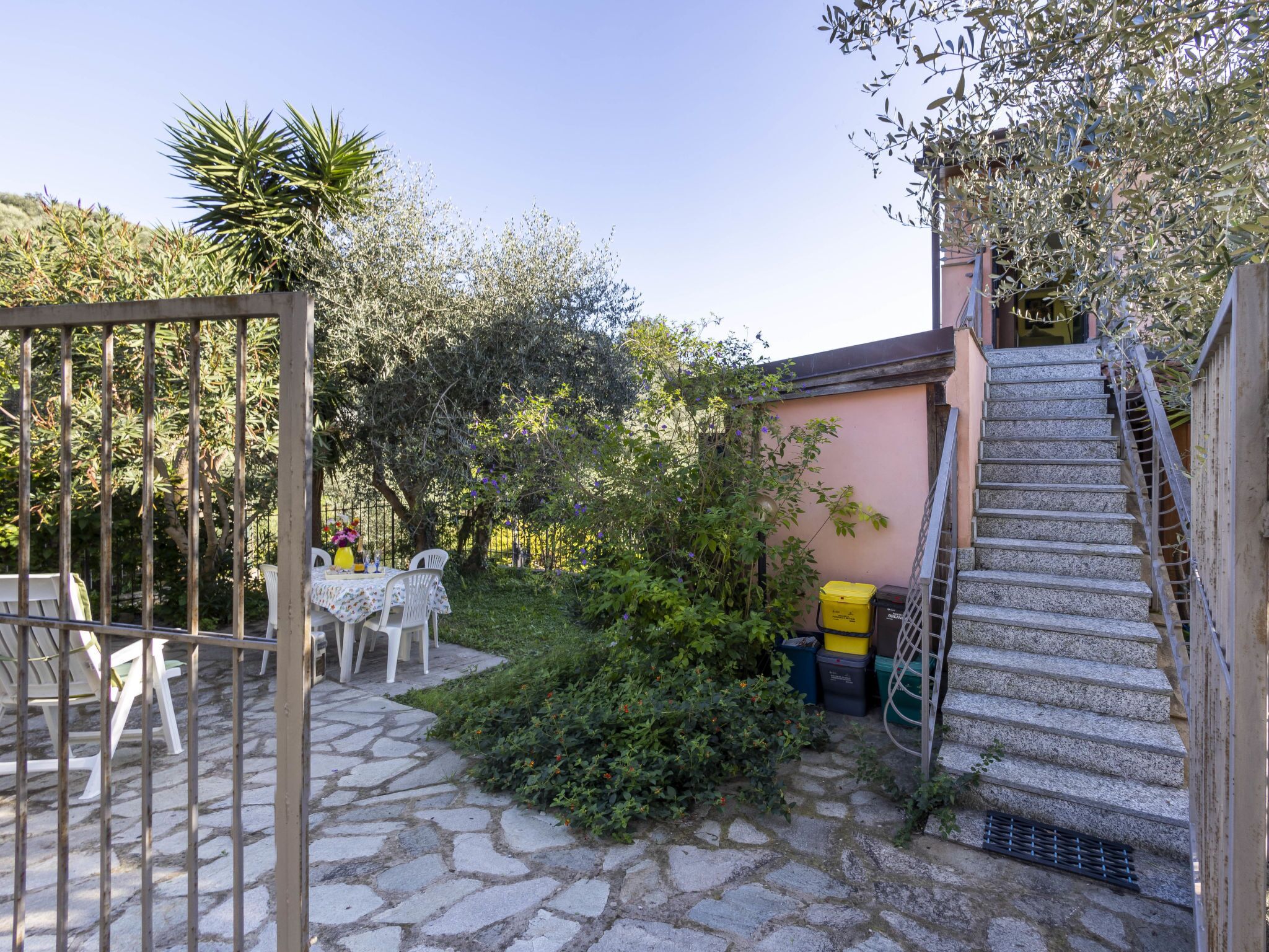 Une terrasse dallée de pierres, dotée d’un espace salon extérieur, d’un escalier et entourée de verdure.