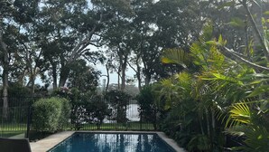 A rectangular pool with a heart drawn on the water, surrounded by lush greenery and trees.