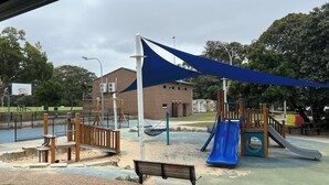A playground with a slide, swings, and a basketball hoop.