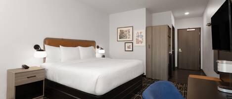 A hotel room with a bed, bedside table, lamp, and a TV.