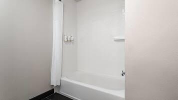 Un baño con una bañera blanca, una cortina de ducha y tres botellas de artículos de aseo en la pared.