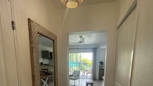 A hallway with a large mirror, a ceiling fan, and a view into a dining area with chairs and a table.