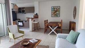 A modern living room with a sofa, a coffee table, and a dining area with a wooden table and chairs.
