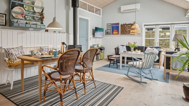 A cozy, well-lit room with a dining area, a kitchen with a stove, and a large window providing natural light.
