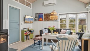 A cozy living room with a fireplace, a sofa, a dining table, and a bookshelf.