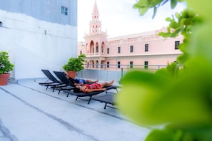Enjoy panoramic views from this rooftop terrace, featuring comfortable lounge chairs and lush greenery.