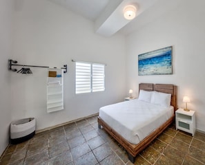 Relax in this serene bedroom with a large bed, bedside tables, and a wall-mounted shelf.