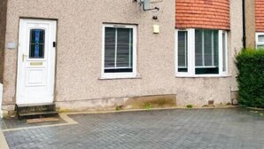 Ein zweistöckiges Wohngebäude mit Ziegelaußenwand, weißen Fensterrahmen und einer kleinen Veranda.