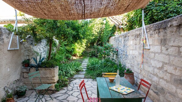 Un patio con mesa, sillas y una sombrilla colgante.