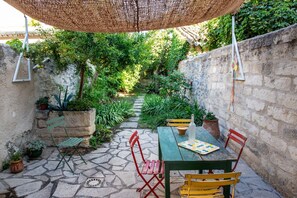 Un patio con mesa, sillas y una sombrilla colgante.