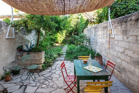 A patio with a table, chairs, and a hanging shade.