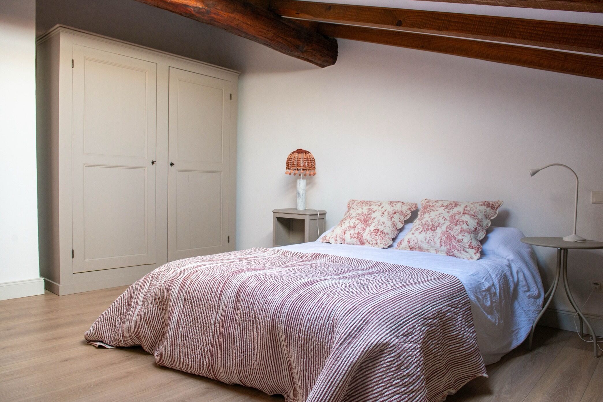 Quarto com cama, duas mesas de cabeceira, luminária e guarda-roupa.