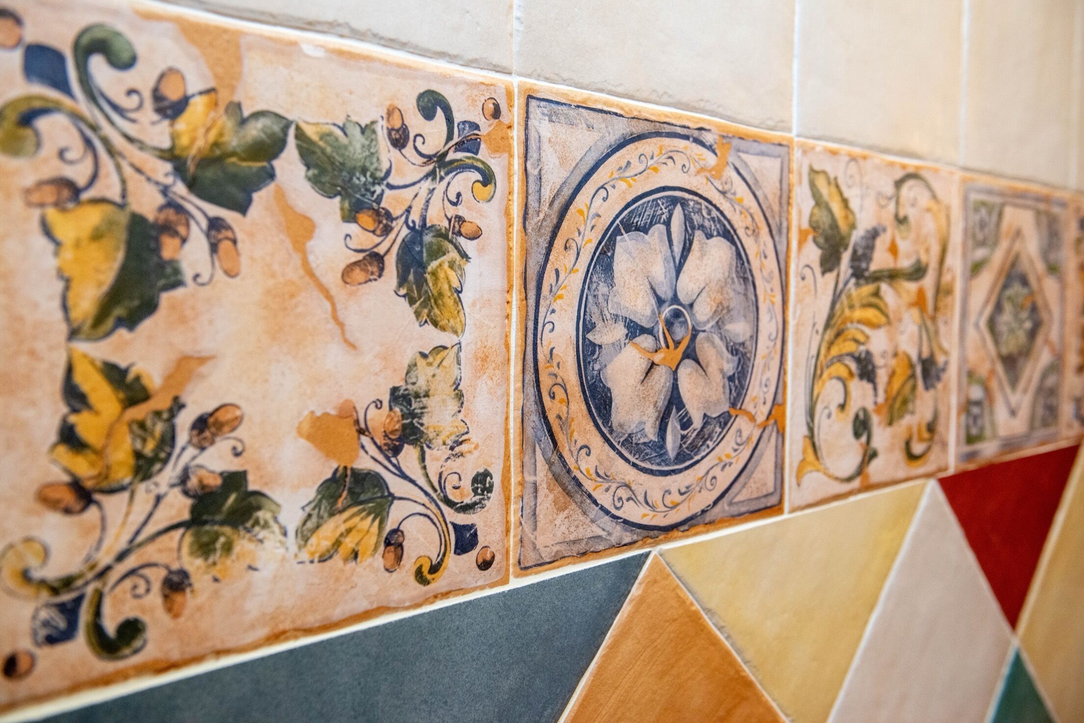 A tiled wall with a variety of patterns and designs, including floral motifs and geometric shapes.
