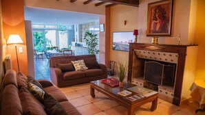 Una sala de estar acogedora con chimenea, un sofá, una mesa de centro y un comedor visible a través de un umbral abierto.