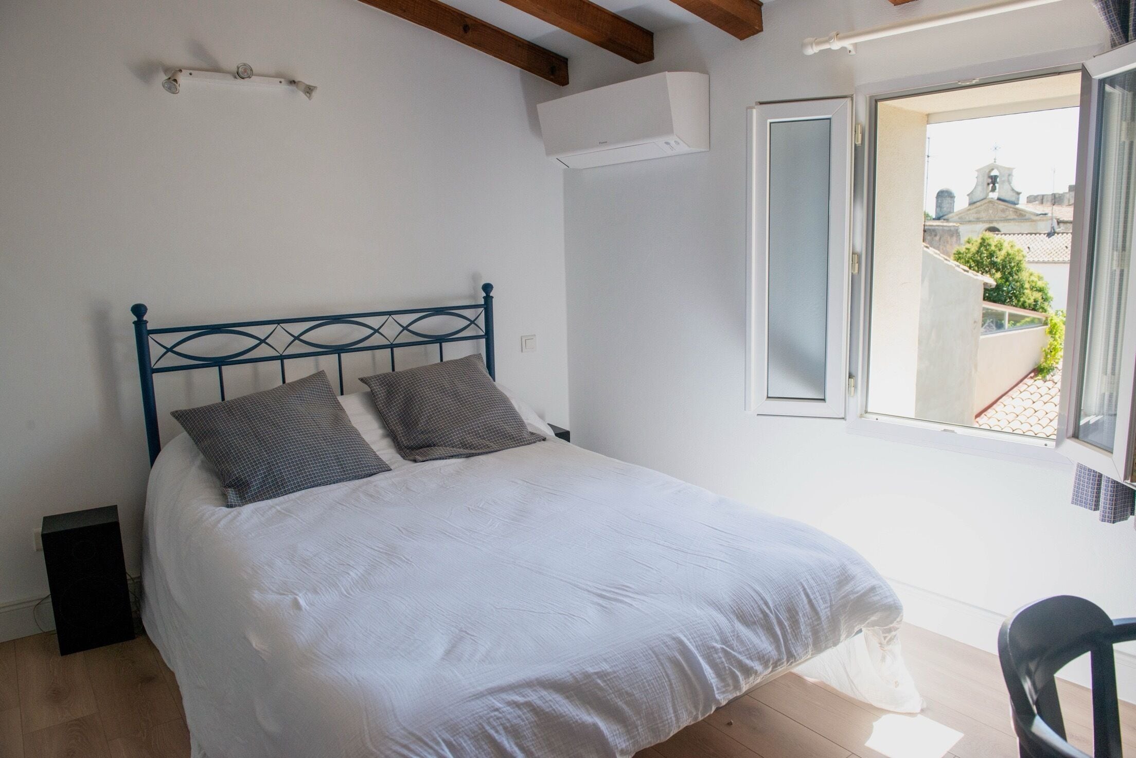 A bedroom with a bed, a window, and a chair.