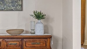 A wooden dresser with drawers and a decorative panel, a vase with green foliage, and a bowl on top. - Downtown Retreat - Cozy Home Near Iconic Downtown (Fargo)