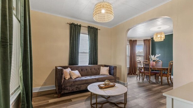A living room with a brown sofa, a round coffee table, and a dining area with a table and chairs. - Downtown Retreat - Cozy Home Near Iconic Downtown (Fargo)