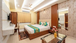 A modern hotel room with a large bed, a desk, a mirror, and a ceiling fan. - Treebo Premium Zorba - Hoshangabad Road (Bhopal)