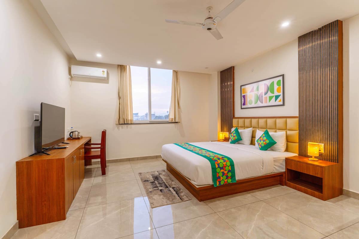 Una habitación de hotel moderna con cama, mesita de noche, televisor y escritorio con silla.
