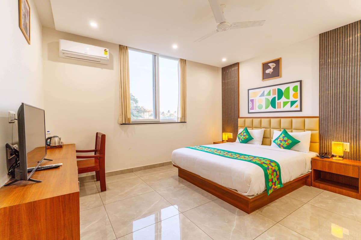 Habitación de hotel con cama, escritorio con computadora, silla, ventana y aire acondicionado instalado en la pared.