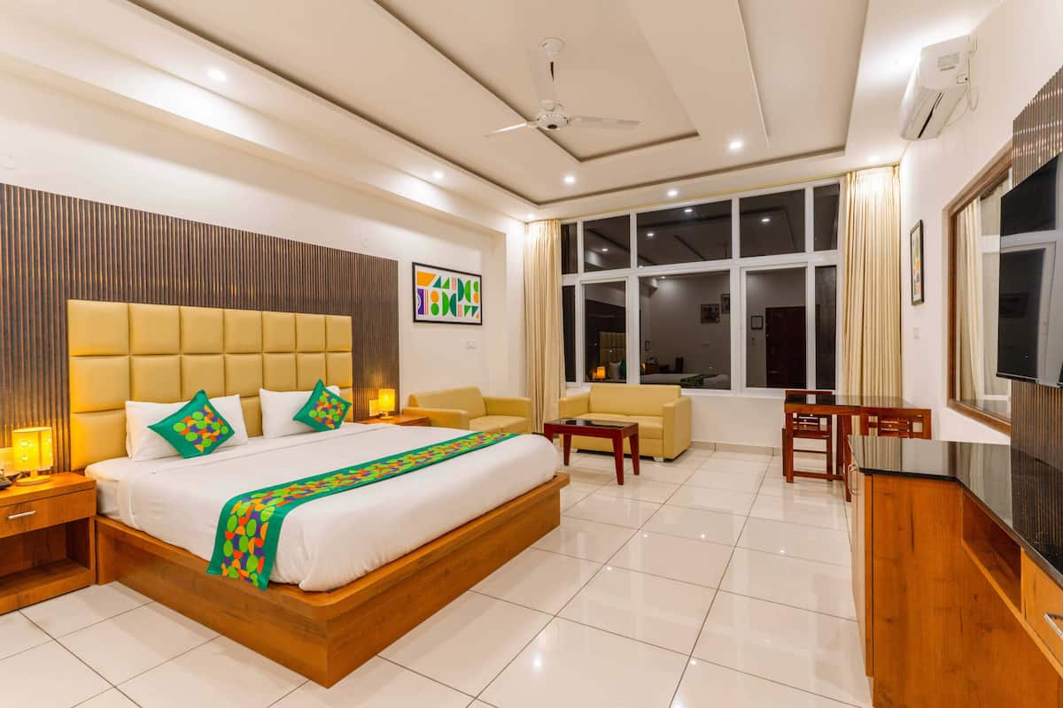 Habitación de hotel con una cama grande, un sofá, un televisor y un escritorio.