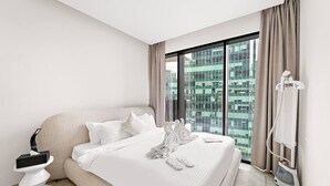 Een moderne hotelkamer met een groot bed, een nachtkastje, een inloopdouche en uitzicht op de stad door middel van ramen van de vloer tot aan het plafond.