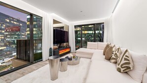 Een moderne woonkamer met een grote bank, een flatscreen televisie en een open haard.