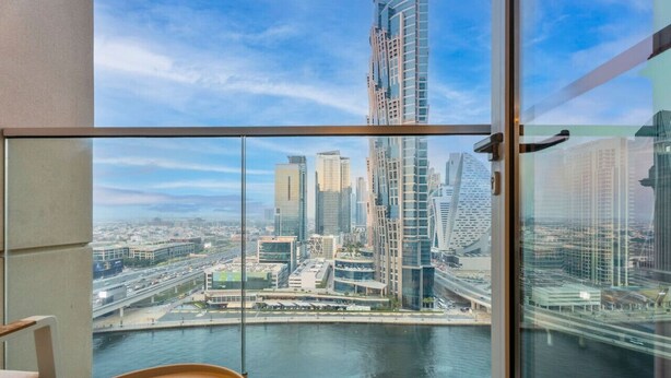 Ein Hotelzimmer in einem Hochhaus mit Panoramablick auf eine Stadtansicht und einen Fluss.