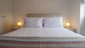 A neatly made bed with white linens and two bedside lamps. - w* | Bright 1BR in Historic Cusco w/ Balcony (Cusco)