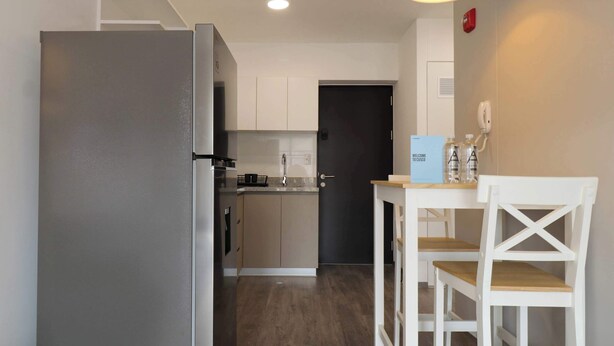 A compact kitchen with a refrigerator, a sink, and a dining area with two chairs. - w* | Bright 1BR in Historic Cusco w/ Balcony (Cusco)