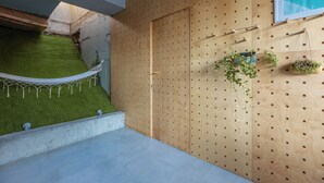 A modern interior with a wooden wall with holes, a hanging plant, and a small garden area. - 3BR Luxury Villa in Tbilisi (shindisi)