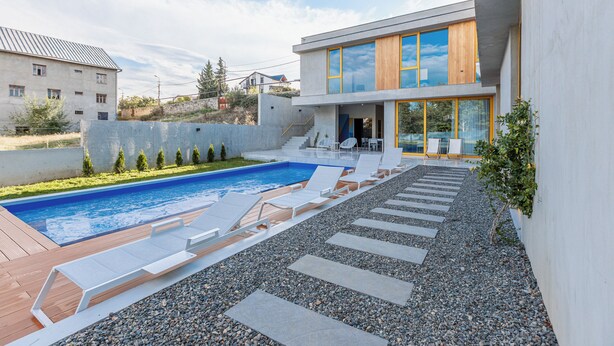 A modern house with a swimming pool, outdoor seating, and a view of neighboring buildings. - 3BR Luxury Villa in Tbilisi (shindisi)
