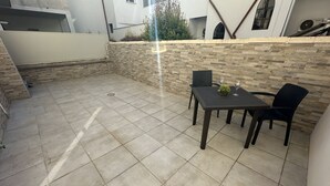 A patio area with a tiled floor, a table with chairs, and a stone wall.