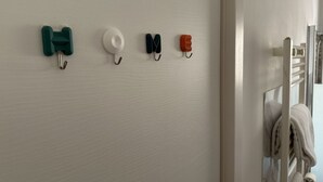 A wall with four hooks, each holding a different item.
