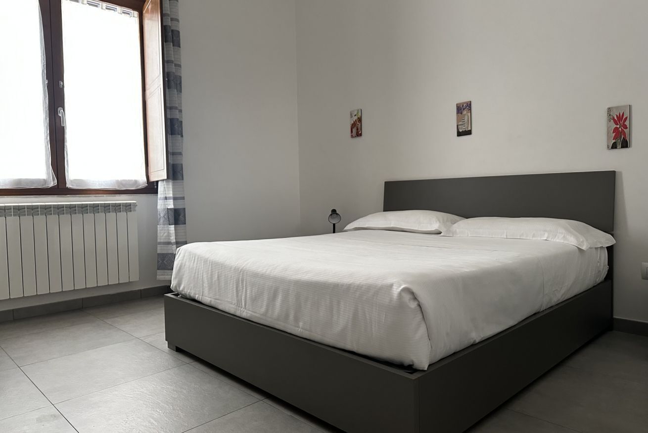 A modern bedroom with a large bed, a radiator, and a window with curtains.