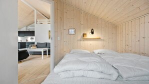 A bedroom with a large bed, a desk, and a kitchenette in the background. - 2 bedroom gorgeous home in Kalundborg (Kalundborg)