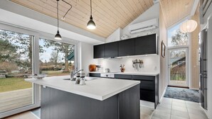 A modern kitchen with a large island, dark cabinetry, and a view of the outdoors. - 2 bedroom gorgeous home in Kalundborg (Kalundborg)