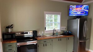 A modern kitchen with stainless steel appliances, wooden countertops, and a built-in oven. - Broyles Landing Cottage at Lake Hartwell SC (Townville)