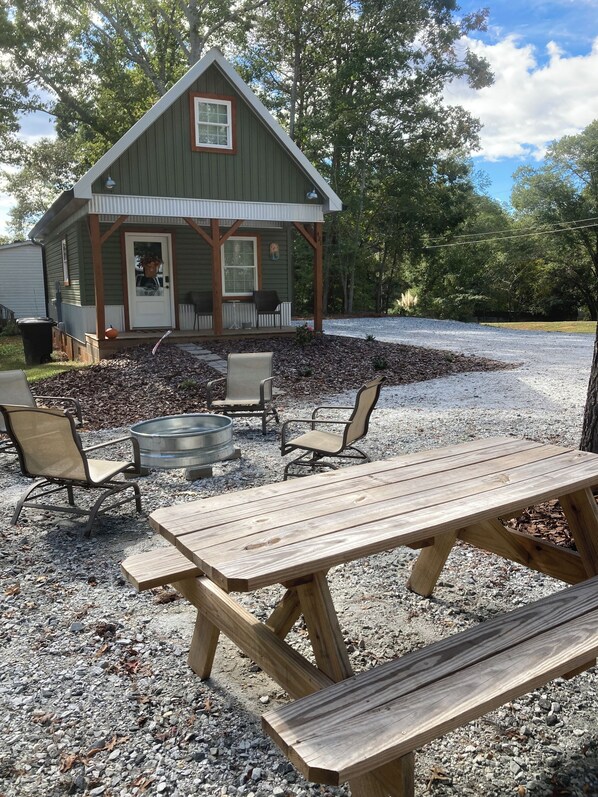 Eine rustikale Holzhütte mit Veranda, Sitzgelegenheit im Freien und Kiesgrund.